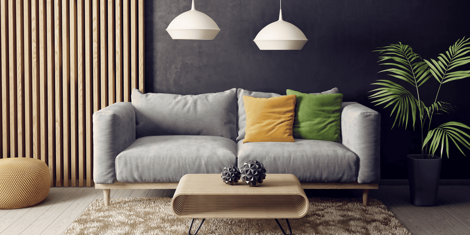 Modern living room with a gray sofa, colorful cushions, a wooden coffee table, and decorative plants.