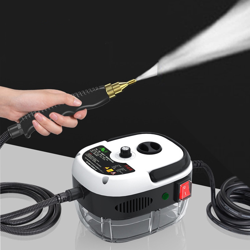 Hand holding a high-pressure washer nozzle with water spray, device on a reflective surface.