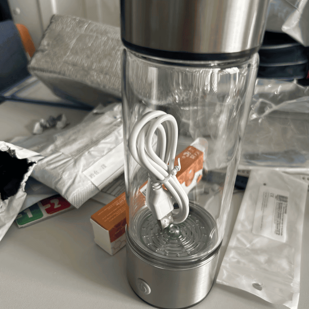 Clear blender with a white cord on a cluttered surface